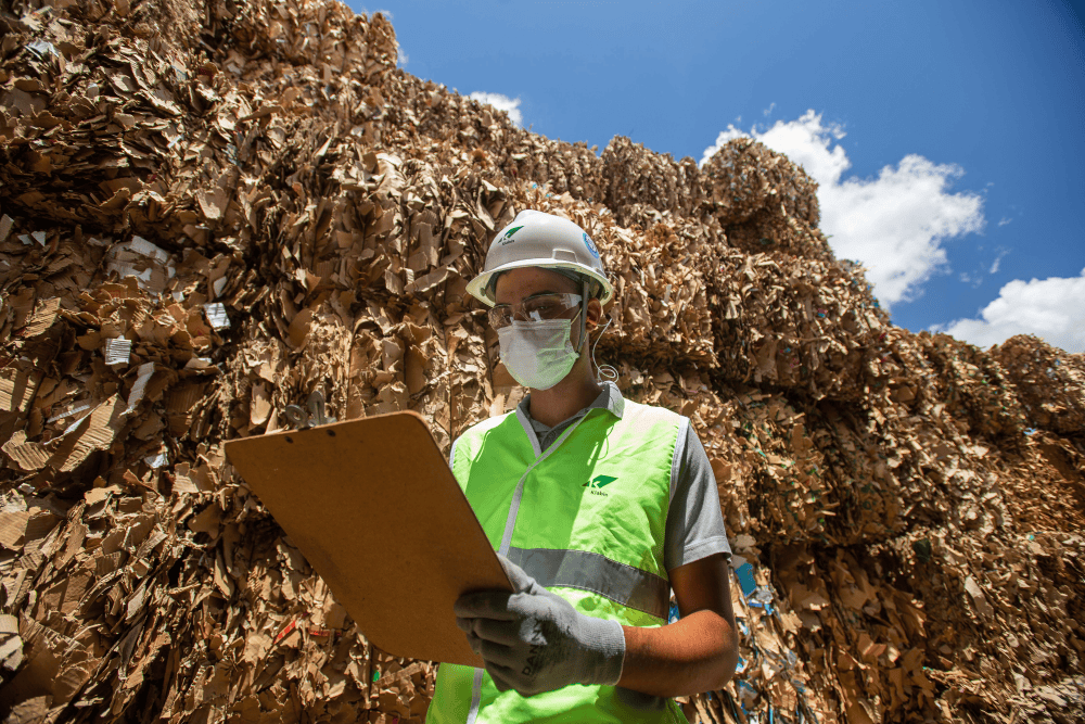 Recycling facility with worker inspecting recycled cardboard and paper materials